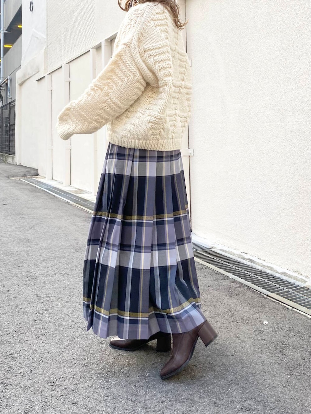 ホワイト系のニット/セーター、ブラウン系のブーツ、ブラック系のスカートを着用したレディースの冬コーディネートの3枚目の写真