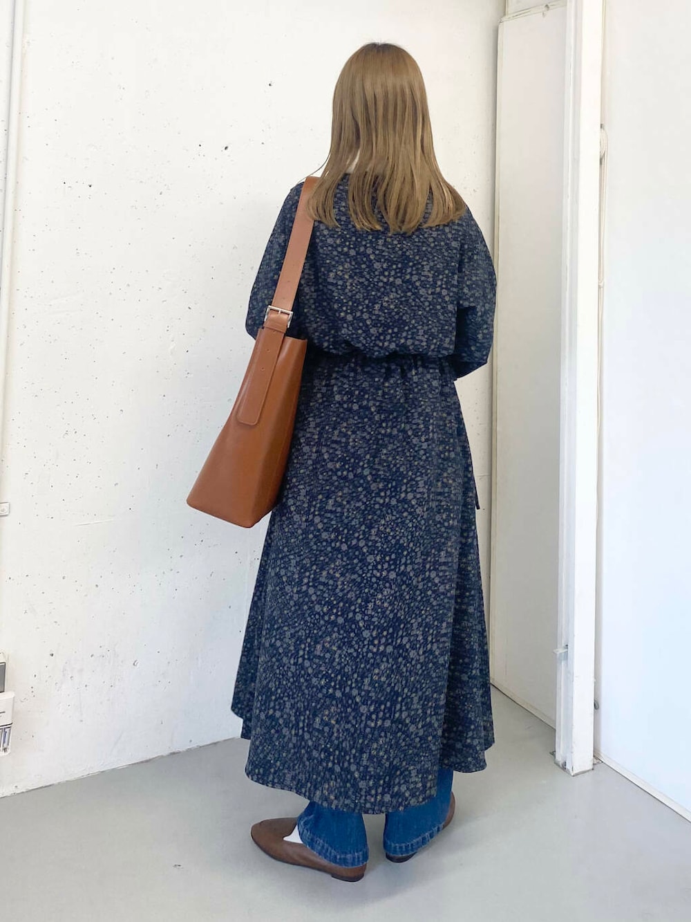 ブラウン系のスリッポン、ブルー系のデニムパンツ、ブラウン系のトートバッグを着用したレディースの秋コーディネートの5枚目の写真