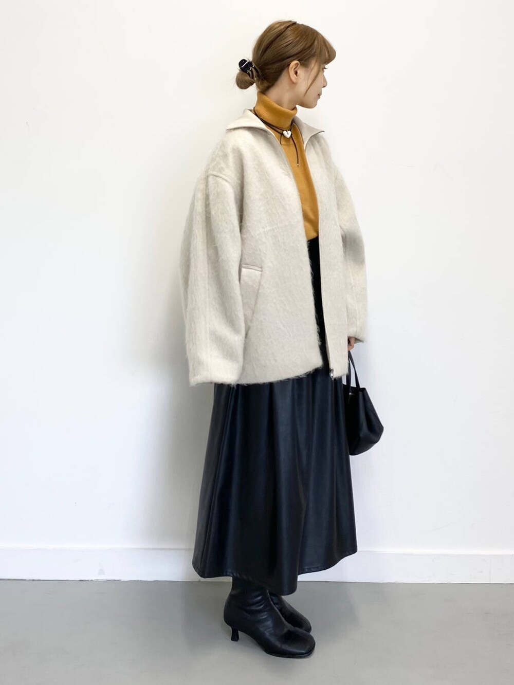 イエロー系のニット/セーター、ブラック系のショルダーバッグ、ブラック系のブーツを着用したレディースの冬コーディネートの7枚目の写真