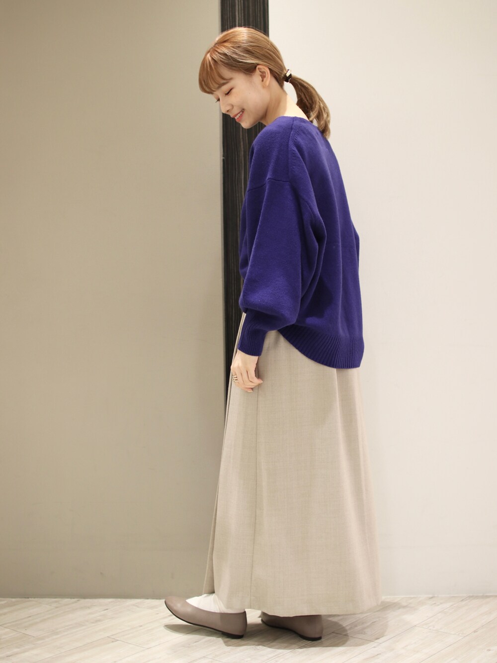 ベージュ系のスカート、グリーン系のショルダーバッグ、ブルー系のニット/セーターを着用したレディースの秋コーディネートの4枚目の写真