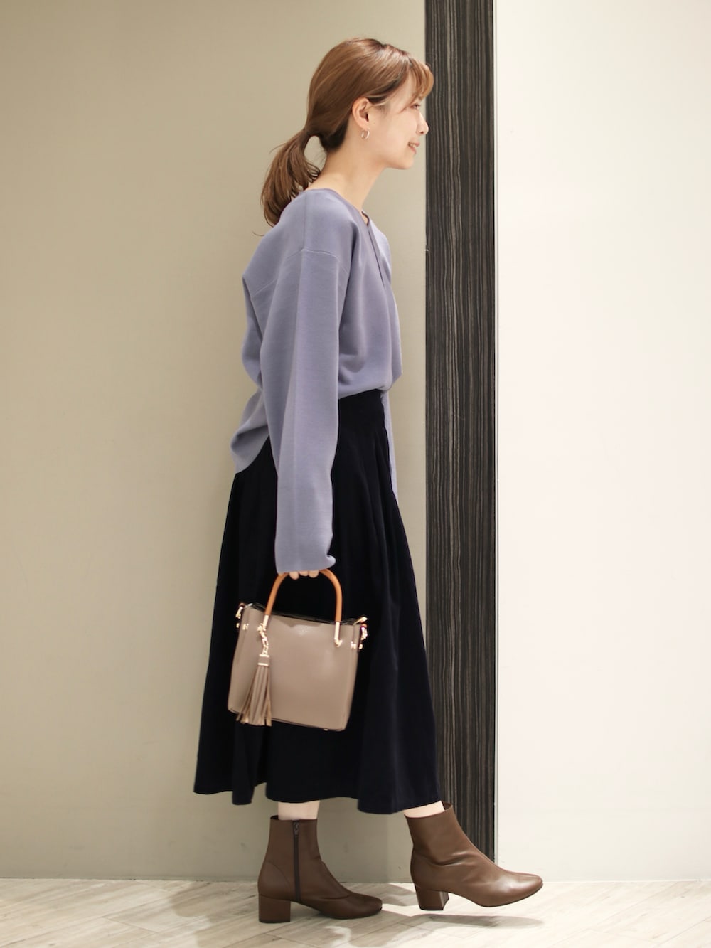 ベージュ系のトートバッグ、ブルー系のスカート、ブルー系のニット/セーターを着用したレディースの秋コーディネートの5枚目の写真