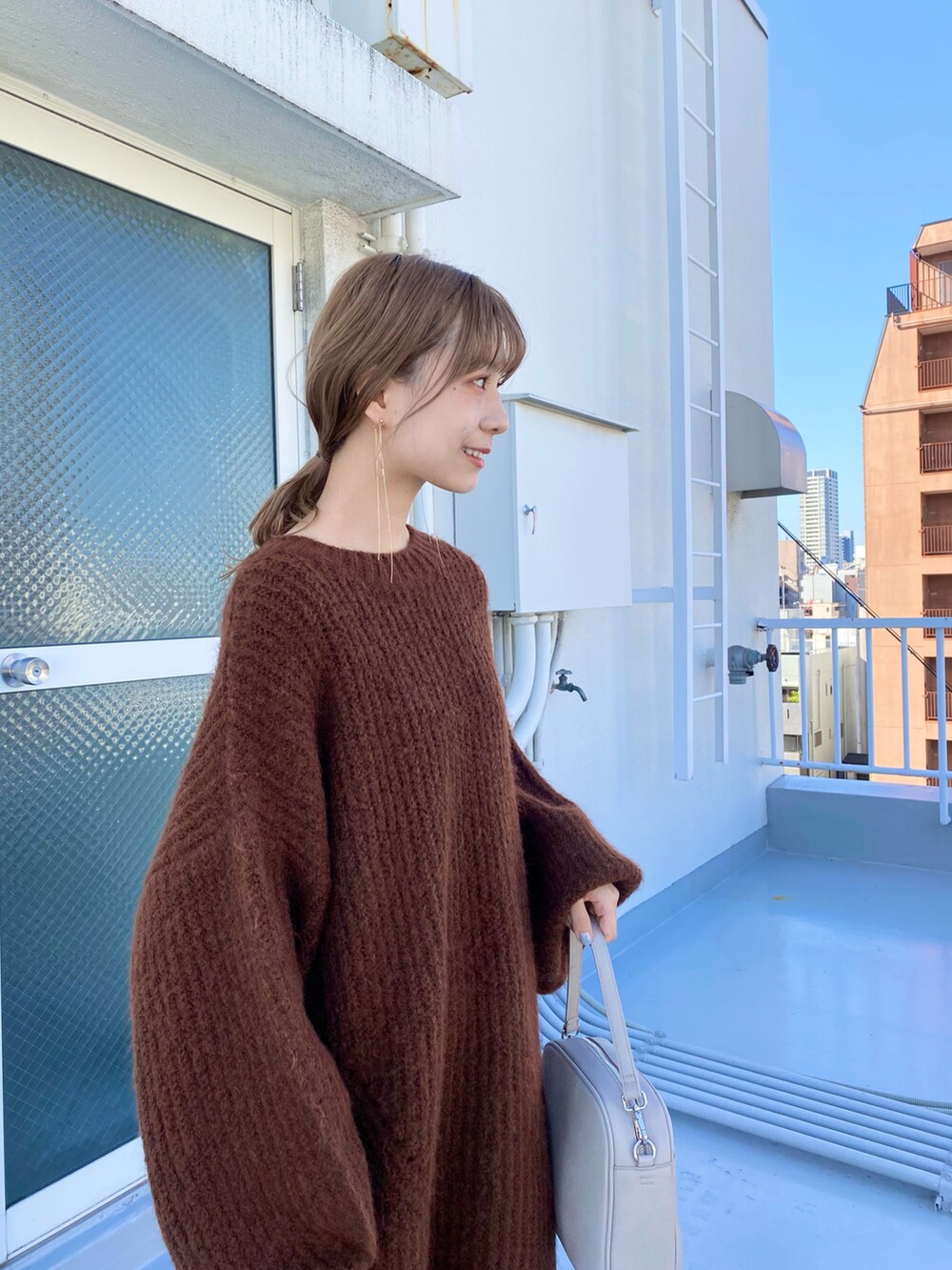 ベージュ系のショルダーバッグ、ブラウン系のブーツ、ブラック系のスカートを着用したレディースの冬コーディネートの5枚目の写真