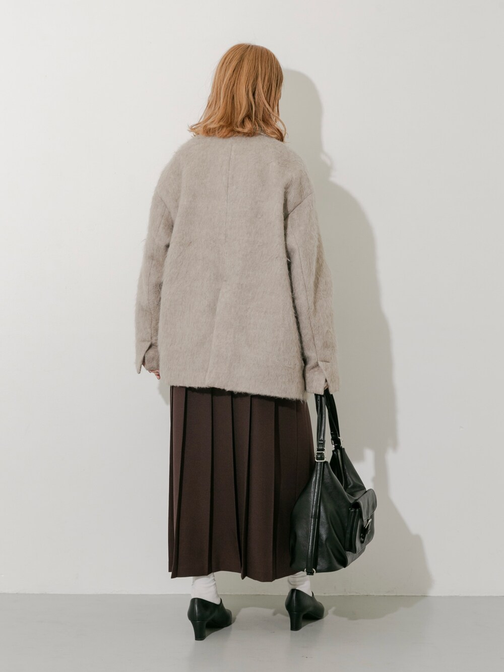 ブラウン系のスカート、ブラウン系のその他アウター、ホワイト系のTシャツ/カットソーを着用したレディースの秋コーディネートの5枚目の写真