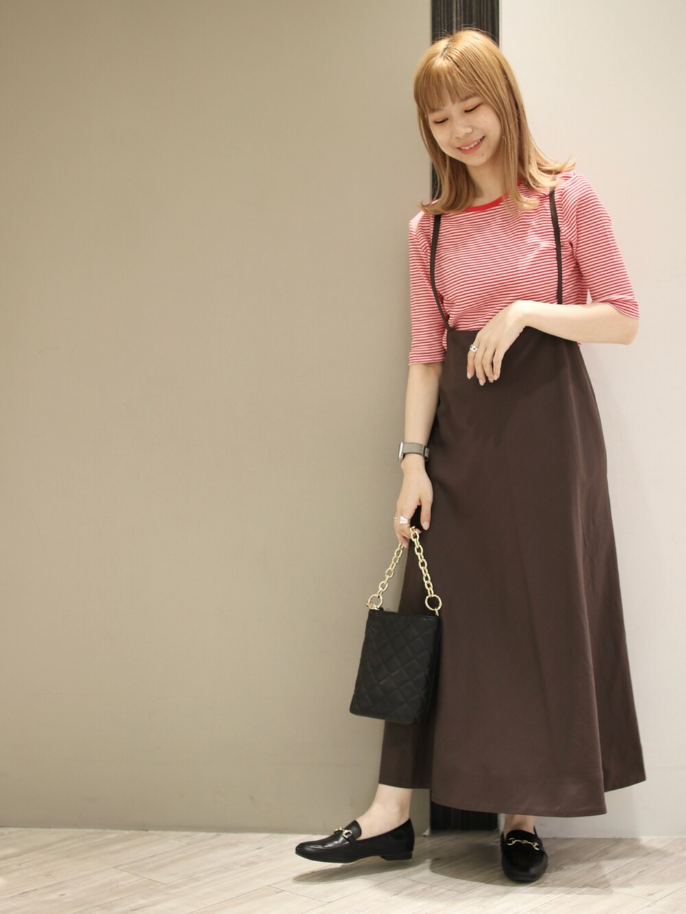ブラック系のショルダーバッグ、ブラウン系のスカート、レッド系のTシャツ/カットソーを着用したレディースの秋コーディネートの3枚目の写真