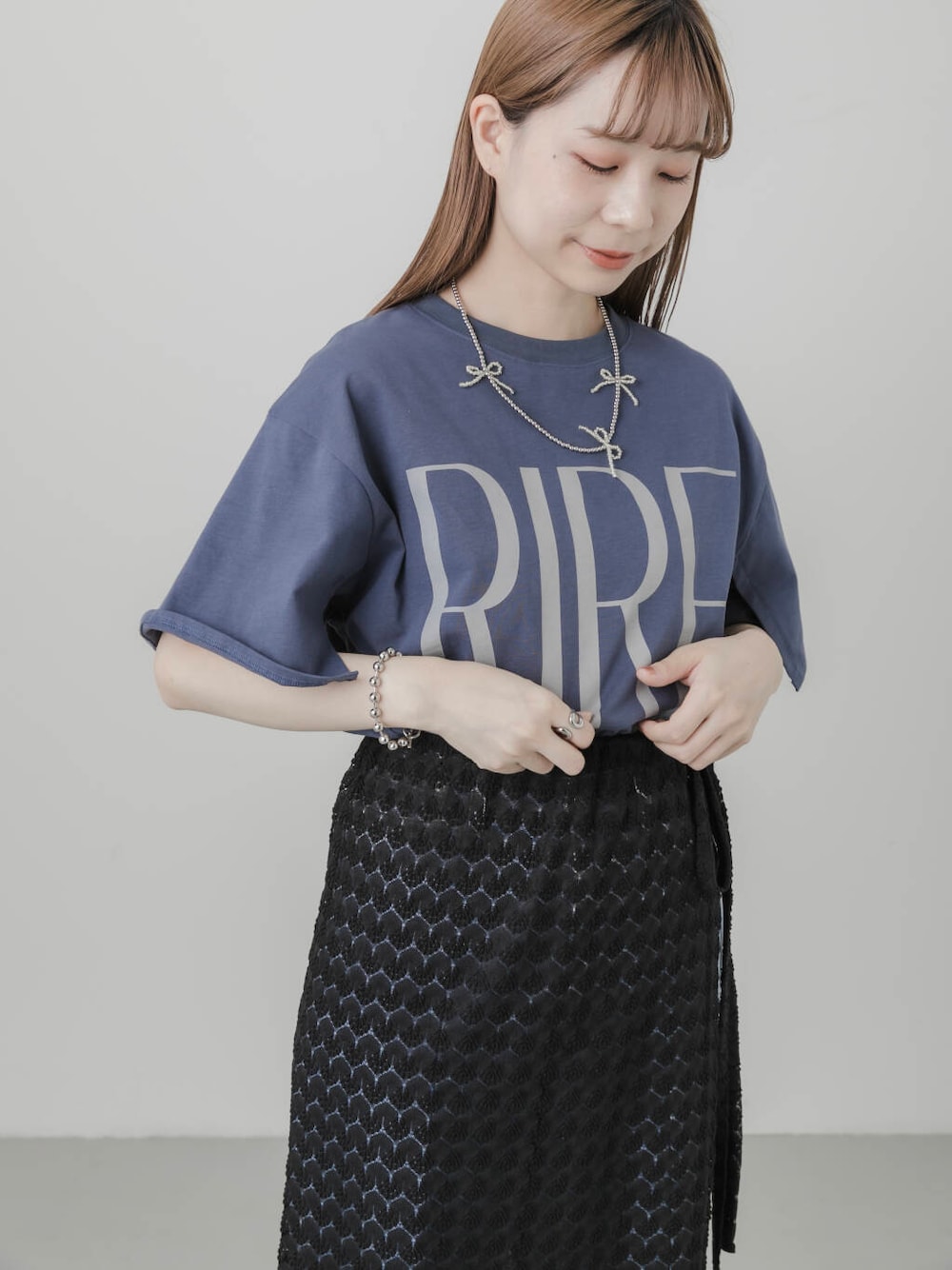 ブルー系のデニムパンツ、ホワイト系のパンプス、ブラック系のスカートを着用したレディースの夏コーディネートの4枚目の写真