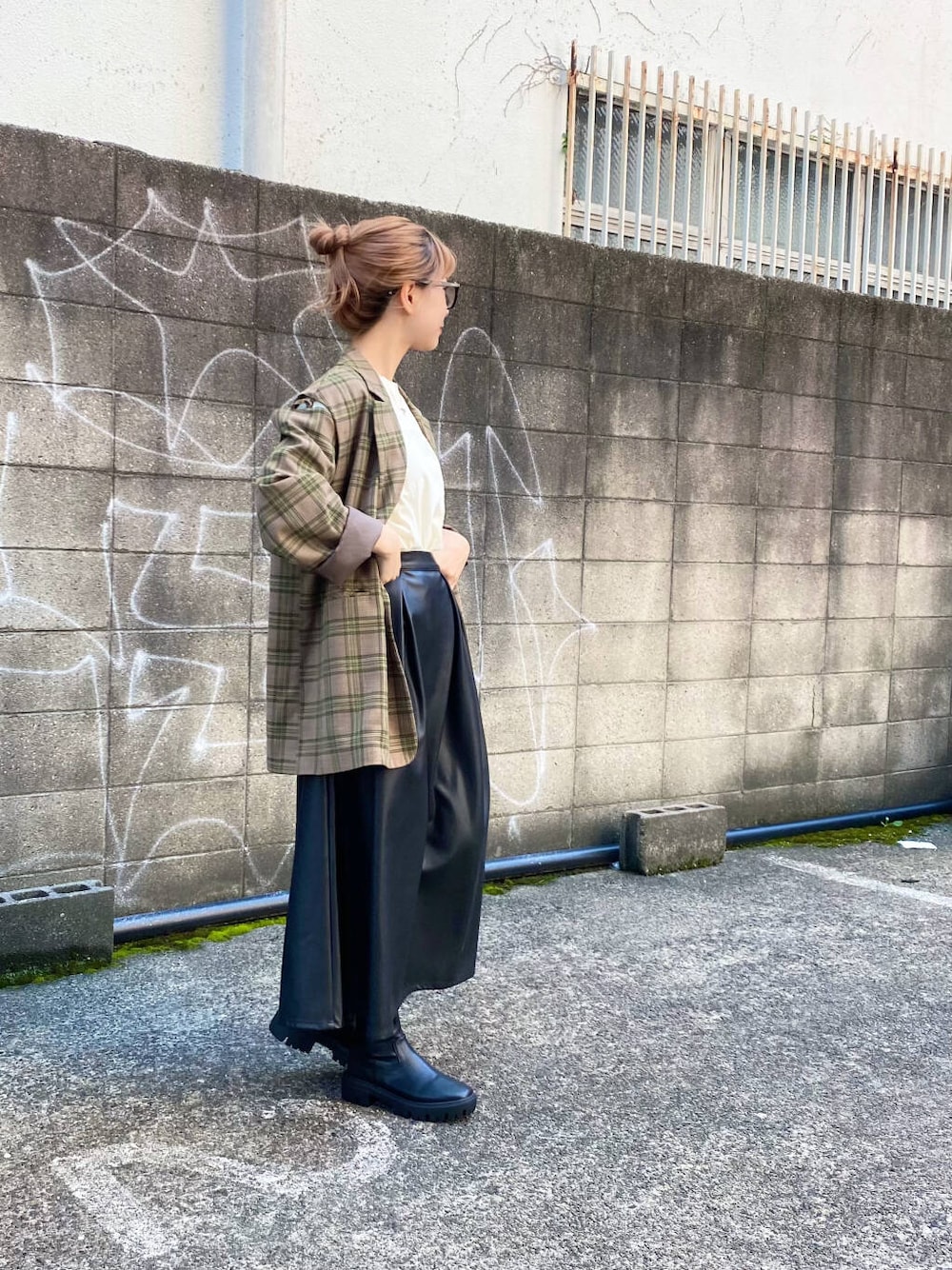 グリーン系のテーラードジャケット、ブラック系のブーツ、ブラック系のスカートを着用したレディースの秋コーディネートの5枚目の写真