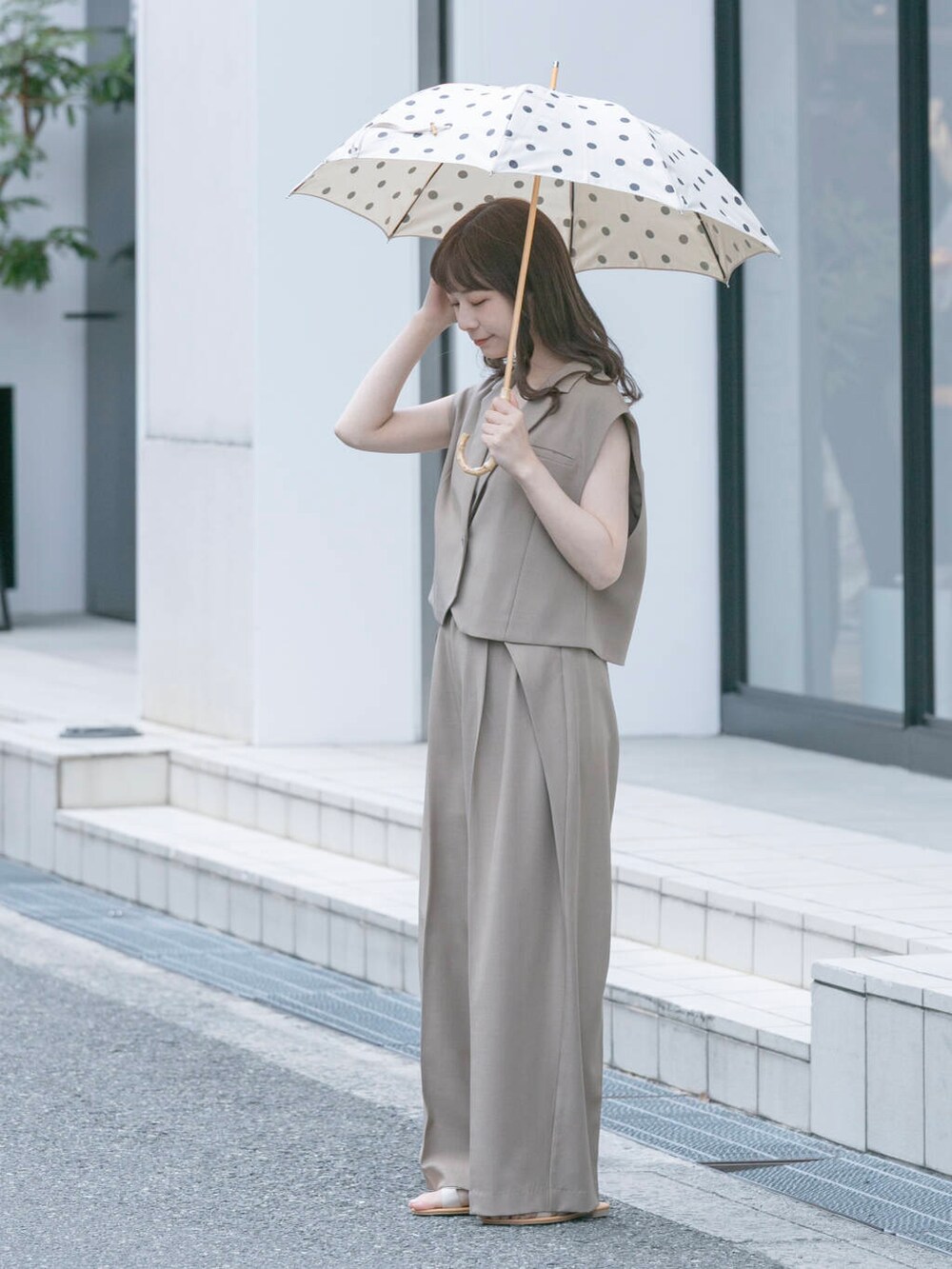 ベージュ系のその他パンツ、ベージュ系のその他アウター、ホワイト系の長傘を着用したレディースの春コーディネートの3枚目の写真