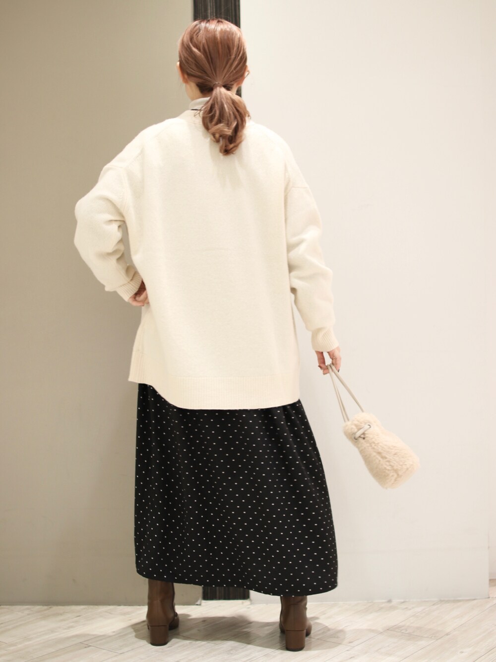 ベージュ系のハンドバッグ、ブラウン系のブーツ、ブラック系のワンピースを着用したレディースの冬コーディネートの3枚目の写真