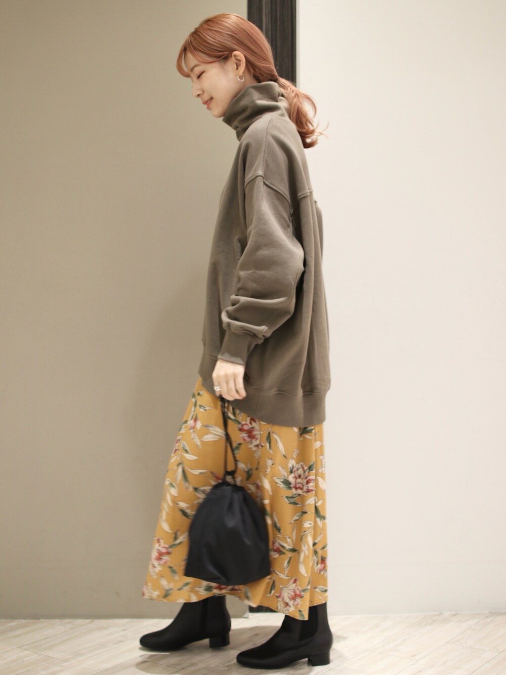 グリーン系のスウェット、オレンジ系のスカート、ブラック系のショルダーバッグを着用したレディースの秋コーディネートの4枚目の写真