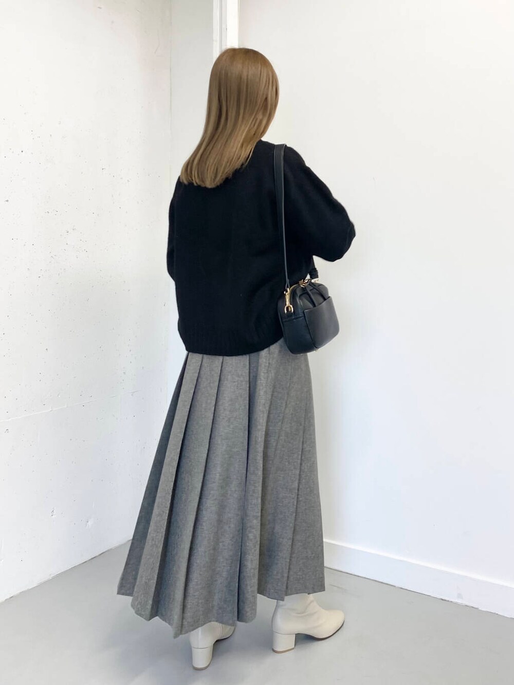 ホワイト系のブーツ、ブラック系のショルダーバッグ、グレー系のスカートを着用したレディースの冬コーディネートの7枚目の写真