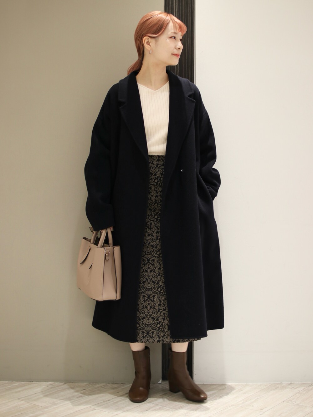 ブラウン系のトートバッグ、ブラック系のスカート、ホワイト系のニット/セーターを着用したレディースの冬コーディネートの2枚目の写真