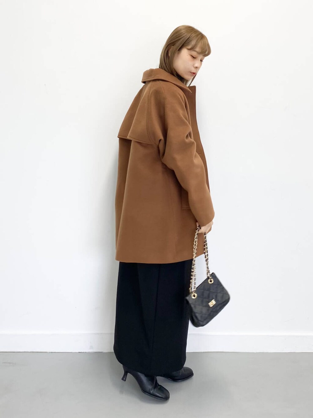 ブラック系のショルダーバッグ、ブラック系のブーツ、ブラック系のワンピースを着用したレディースの冬コーディネートの3枚目の写真