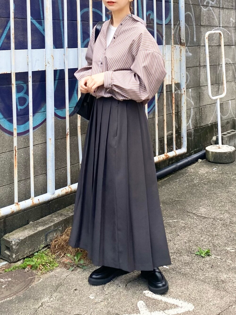 グレー系のスカート、ブラウン系のシャツ/ブラウス、ブラック系のローファーを着用したレディースの秋コーディネートの5枚目の写真