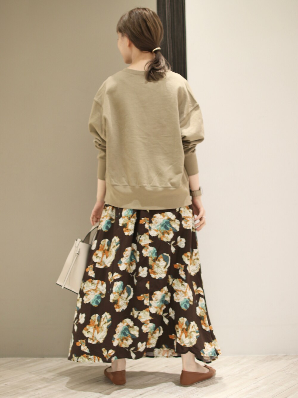 ホワイト系のトートバッグ、ベージュ系のスウェット、ブラウン系のスカートを着用したレディースの秋コーディネートの2枚目の写真