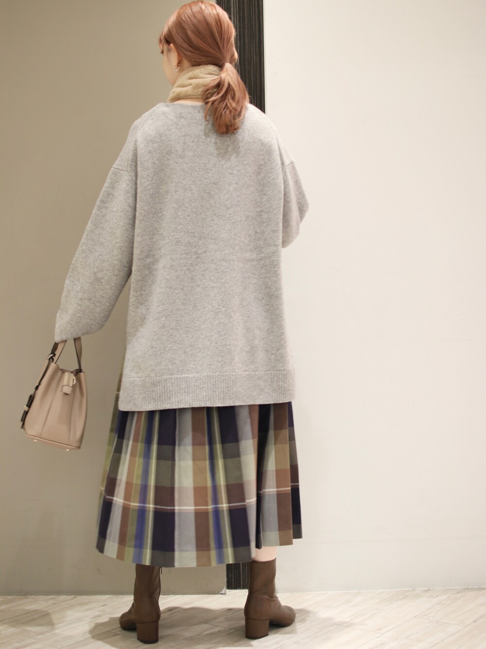 ブルー系のスカート、ベージュ系のトートバッグ、グレー系のニット/セーターを着用したレディースの秋コーディネートの4枚目の写真