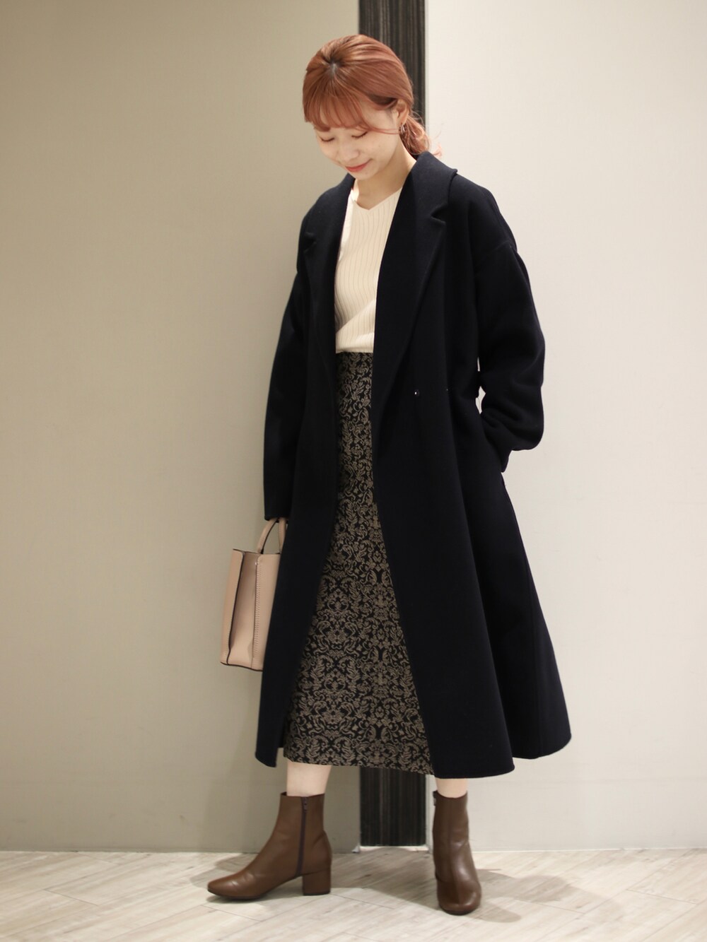 ブラウン系のトートバッグ、ブラック系のスカート、ホワイト系のニット/セーターを着用したレディースの冬コーディネートの4枚目の写真