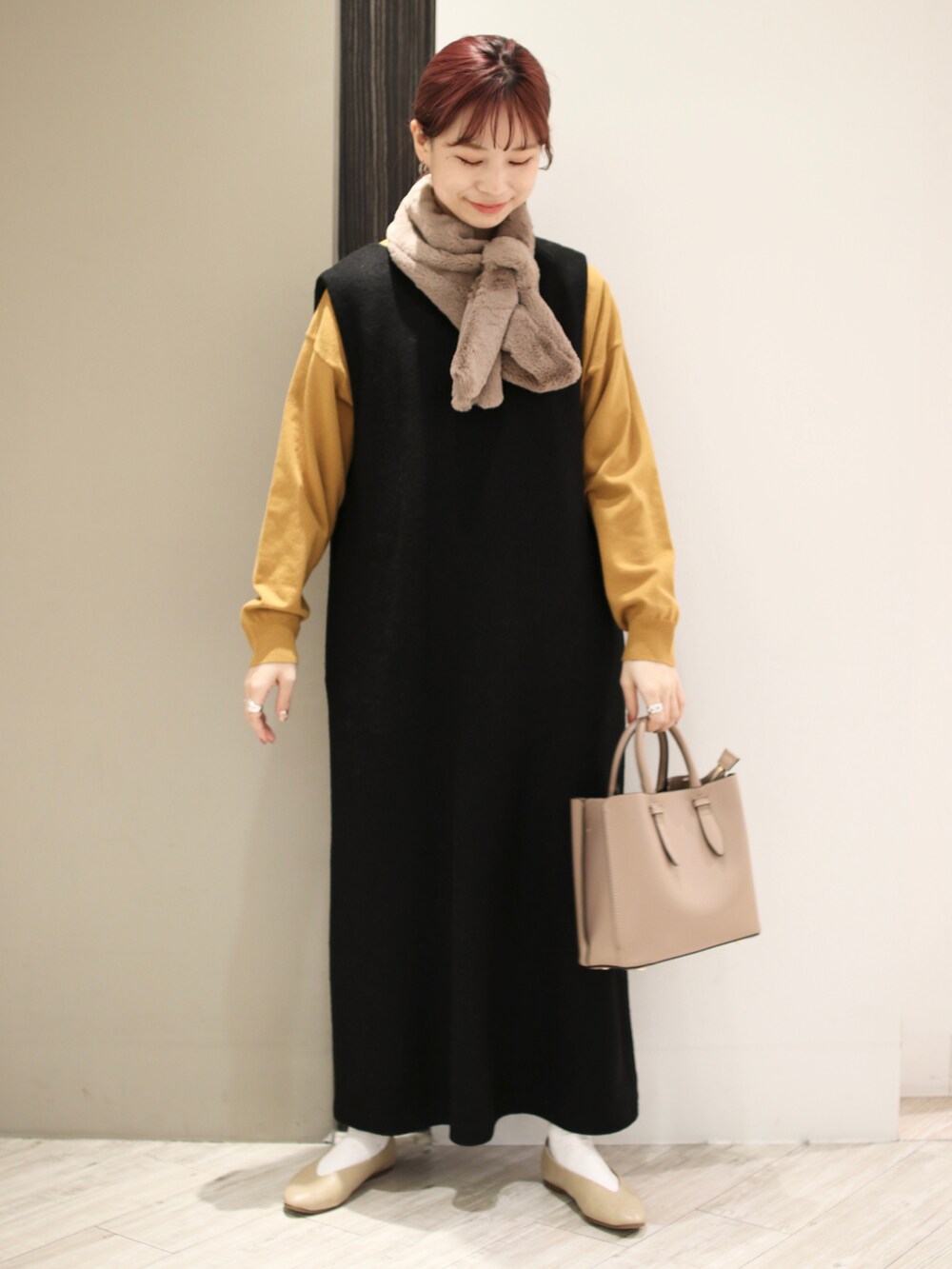 ブラウン系のトートバッグ、ブラック系のワンピース、イエロー系のニット/セーターを着用したレディースの冬コーディネートの2枚目の写真