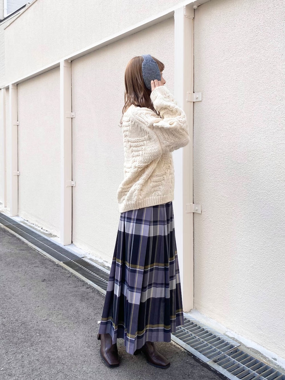 ホワイト系のニット/セーター、ブラウン系のブーツ、ブラック系のスカートを着用したレディースの冬コーディネートの6枚目の写真