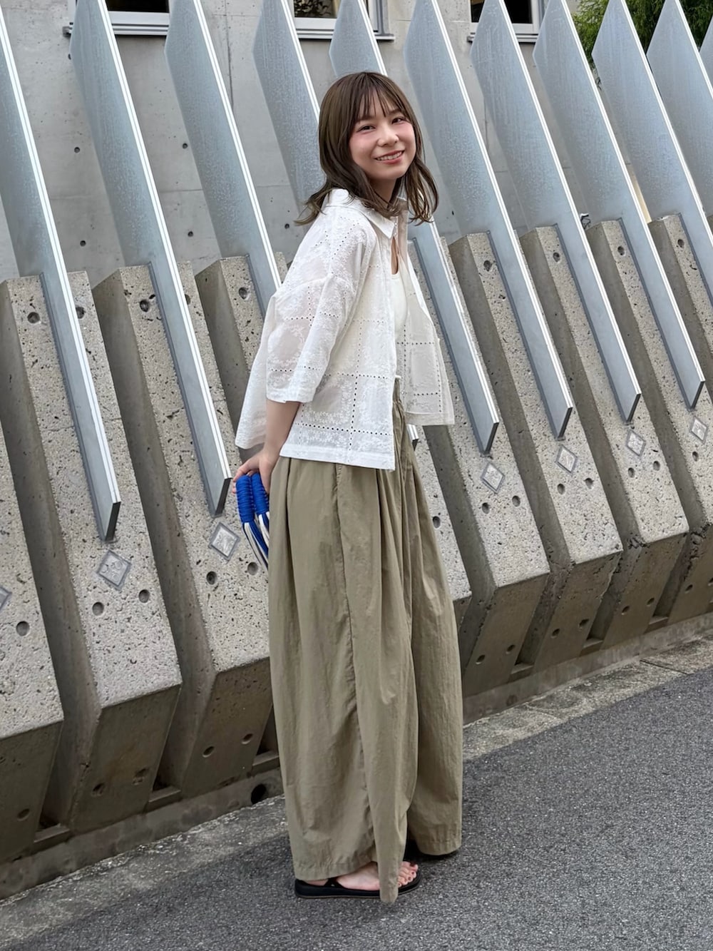 ベージュ系のその他パンツ、ブラック系のサンダル、ブルー系のハンドバッグを着用したレディースの秋コーディネートの2枚目の写真