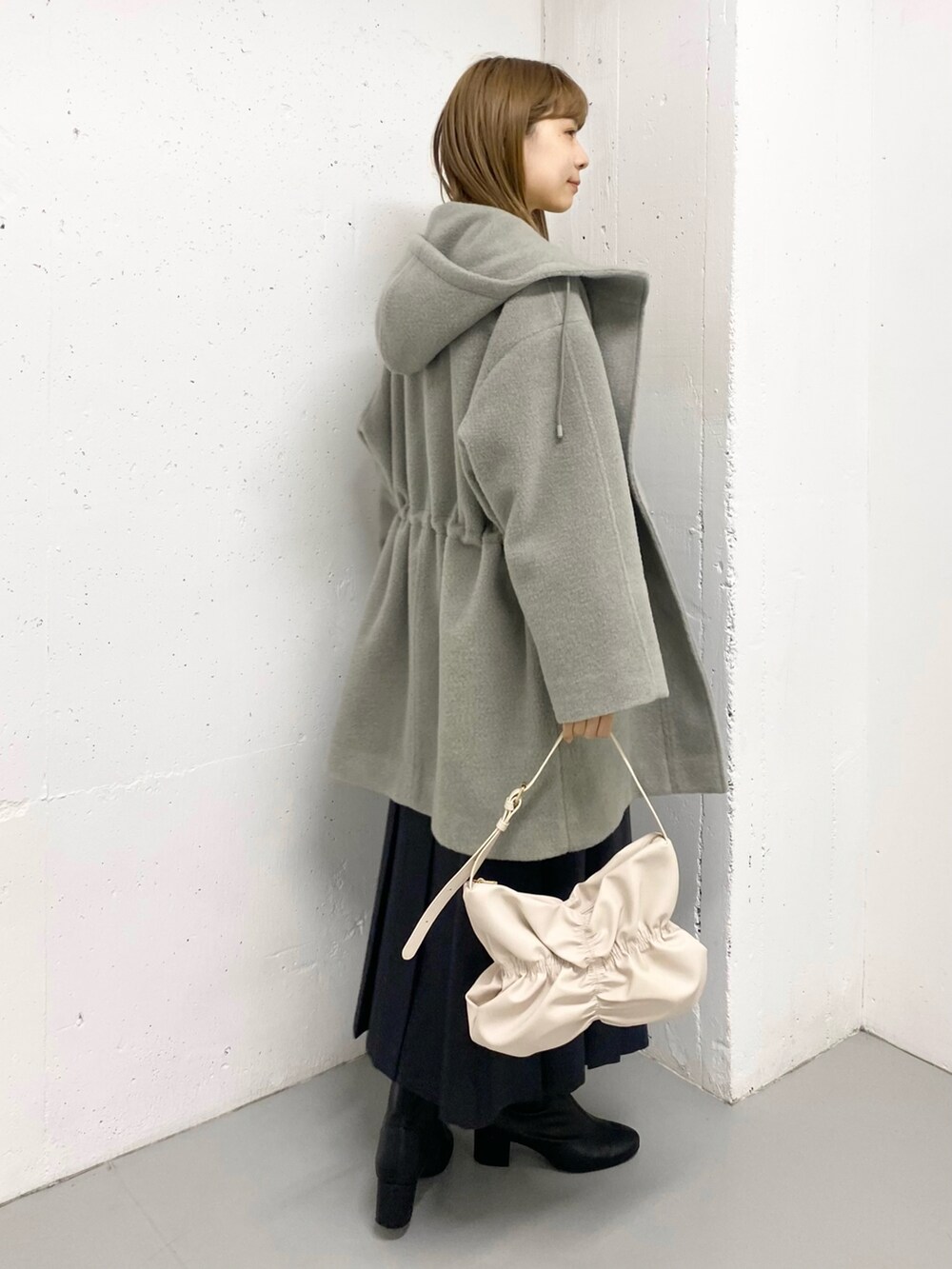 グリーン系のその他アウター、ホワイト系のニット/セーター、ブラック系のブーツを着用したレディースの冬コーディネートの5枚目の写真