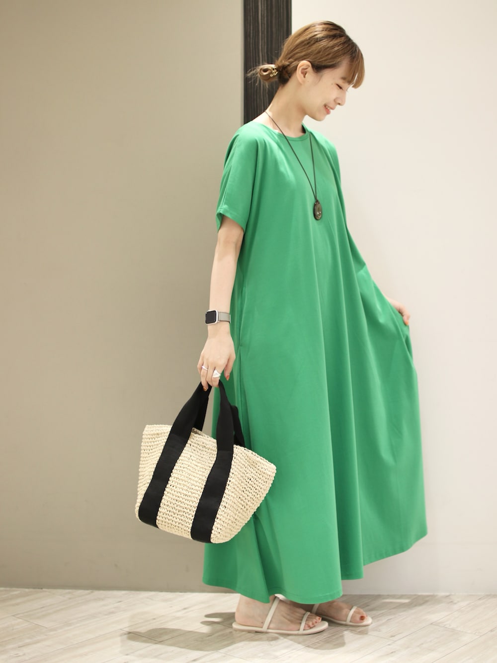 ベージュ系のトートバッグ、ホワイト系のサンダル、グリーン系のワンピースを着用したレディースの夏コーディネートの3枚目の写真