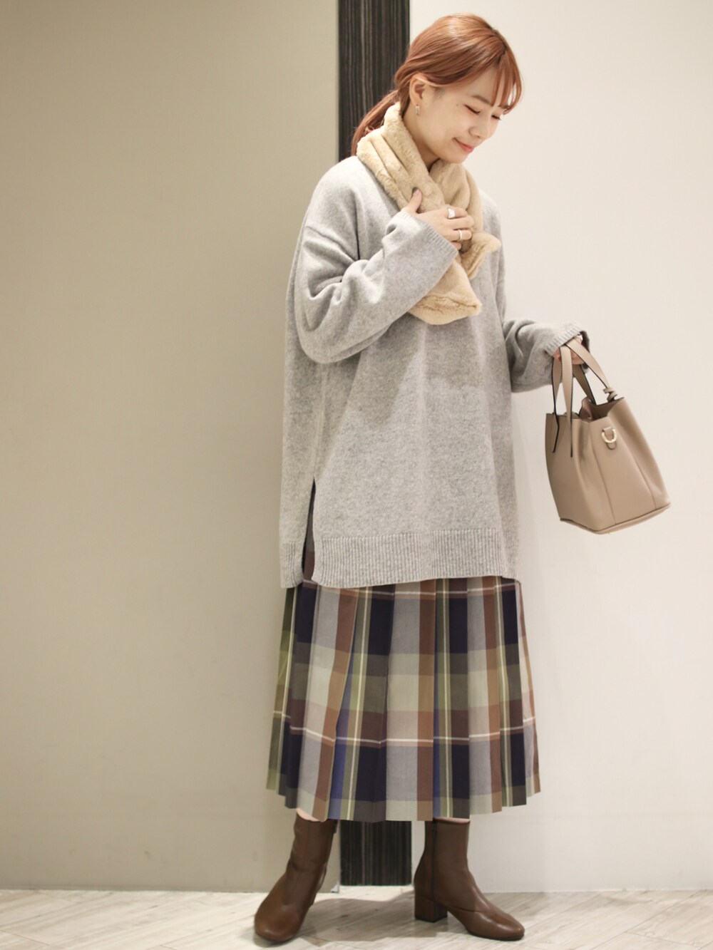 ブルー系のスカート、ベージュ系のトートバッグ、グレー系のニット/セーターを着用したレディースの秋コーディネートの2枚目の写真