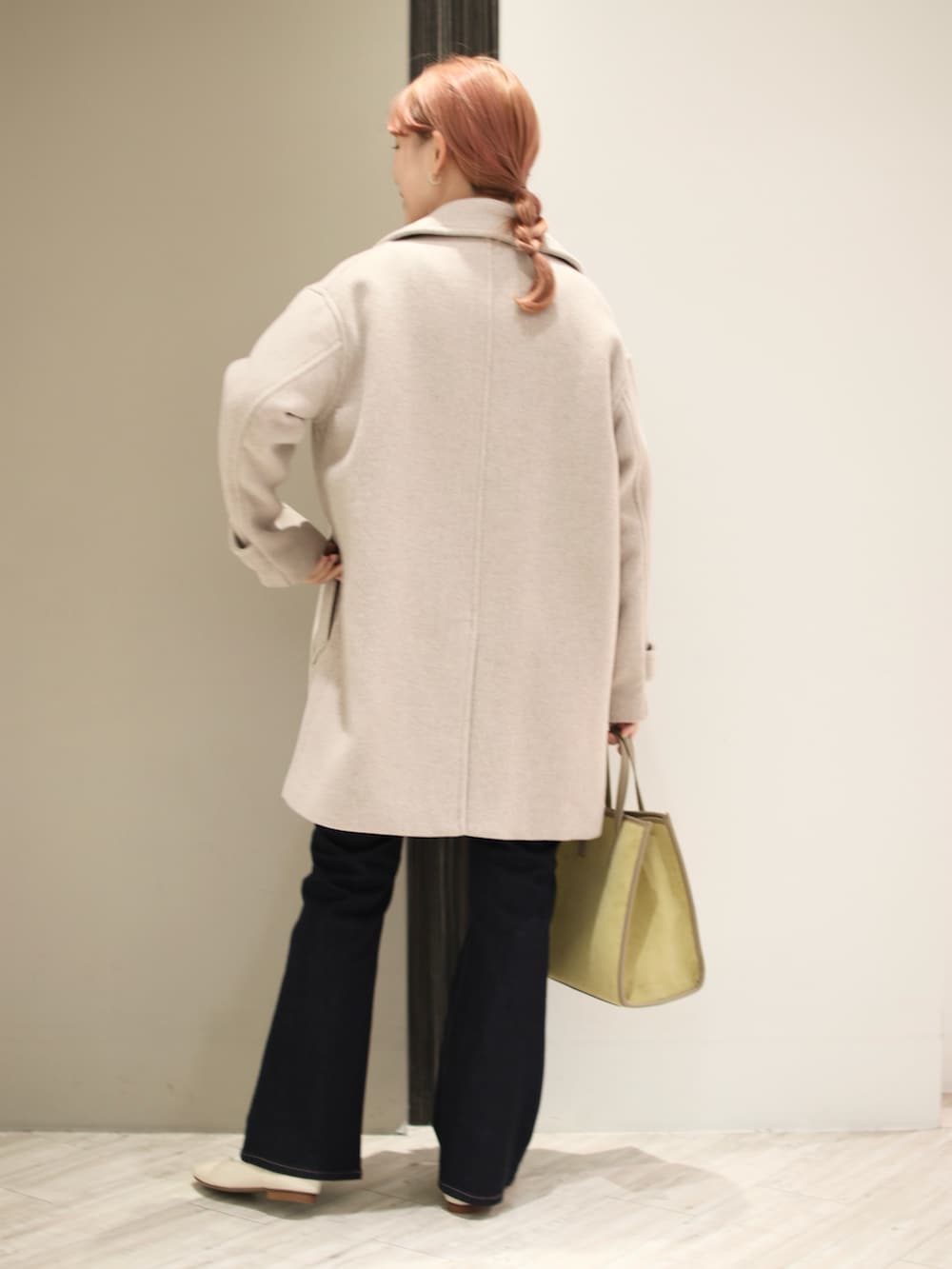 ブルー系のデニムパンツ、イエロー系のショルダーバッグ、ホワイト系のパンプスを着用したレディースの冬コーディネートの3枚目の写真