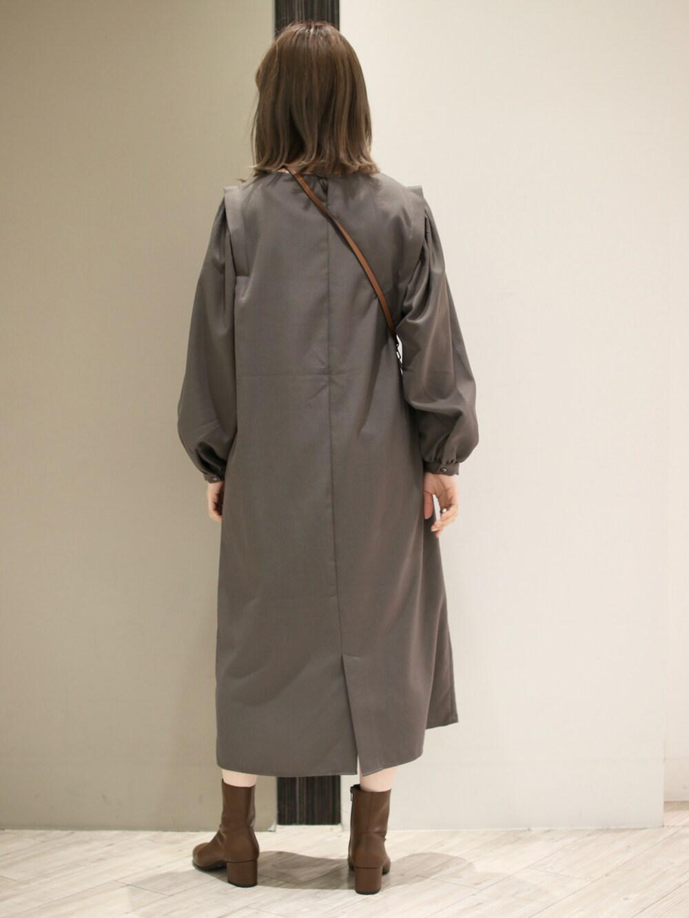 グレー系のワンピース、ブラウン系のブーツ、ブラウン系のショルダーバッグを着用したレディースの冬コーディネートの4枚目の写真