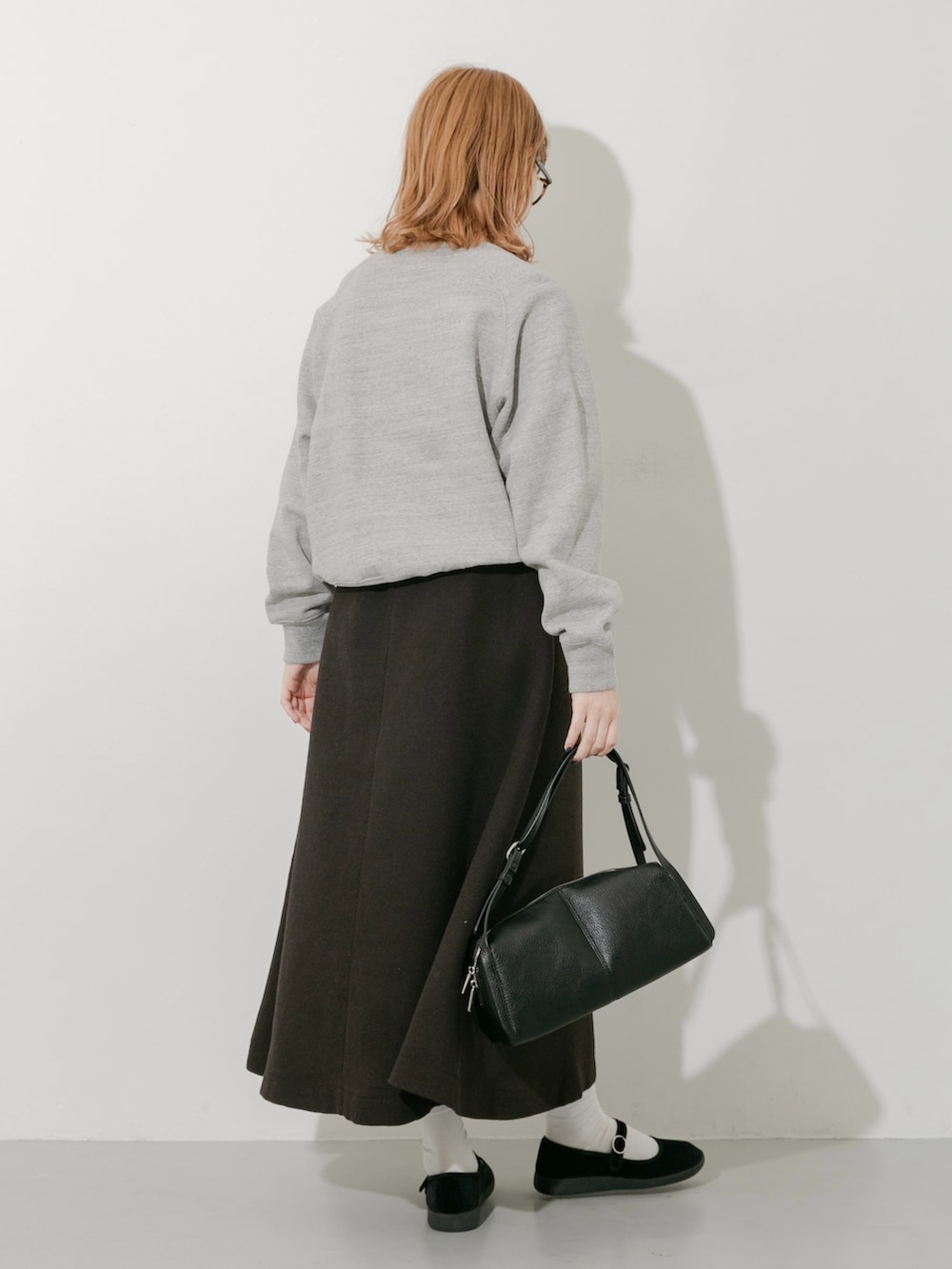 グレー系のスカート、ブラック系のその他シューズ、グレー系のスウェットを着用したレディースの秋コーディネートの5枚目の写真