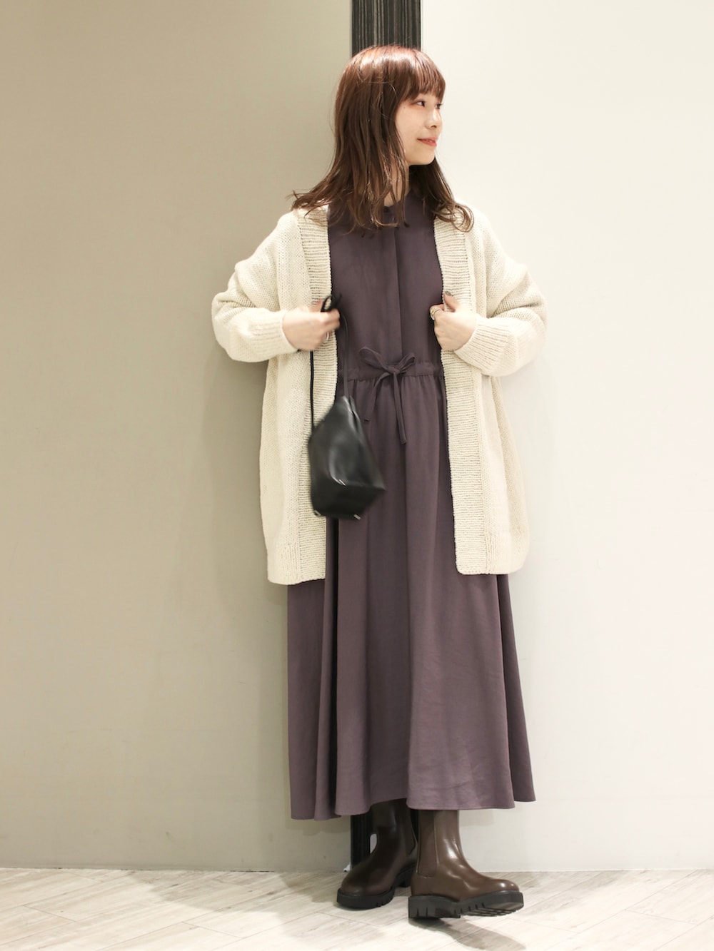 グレー系のワンピース、ホワイト系のカーディガン/ボレロ、ブラック系のショルダーバッグを着用したレディースの冬コーディネートの4枚目の写真