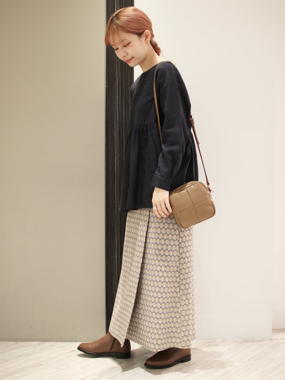 イエロー系のスカート、ブラウン系のブーツ、グレー系のシャツ/ブラウスを着用したレディースの冬コーディネートの3枚目の写真