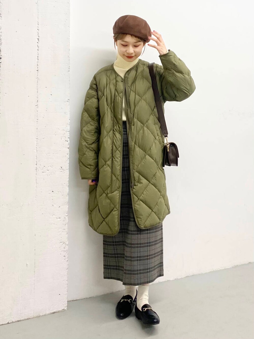 ブラック系のローファー、グリーン系のダウンジャケット/コート、ブラウン系のショルダーバッグを着用したレディースの冬コーディネートの3枚目の写真