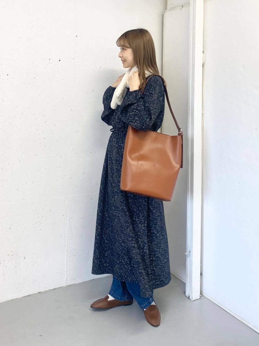 ブラウン系のスリッポン、ブルー系のデニムパンツ、ブラウン系のトートバッグを着用したレディースの秋コーディネートの2枚目の写真