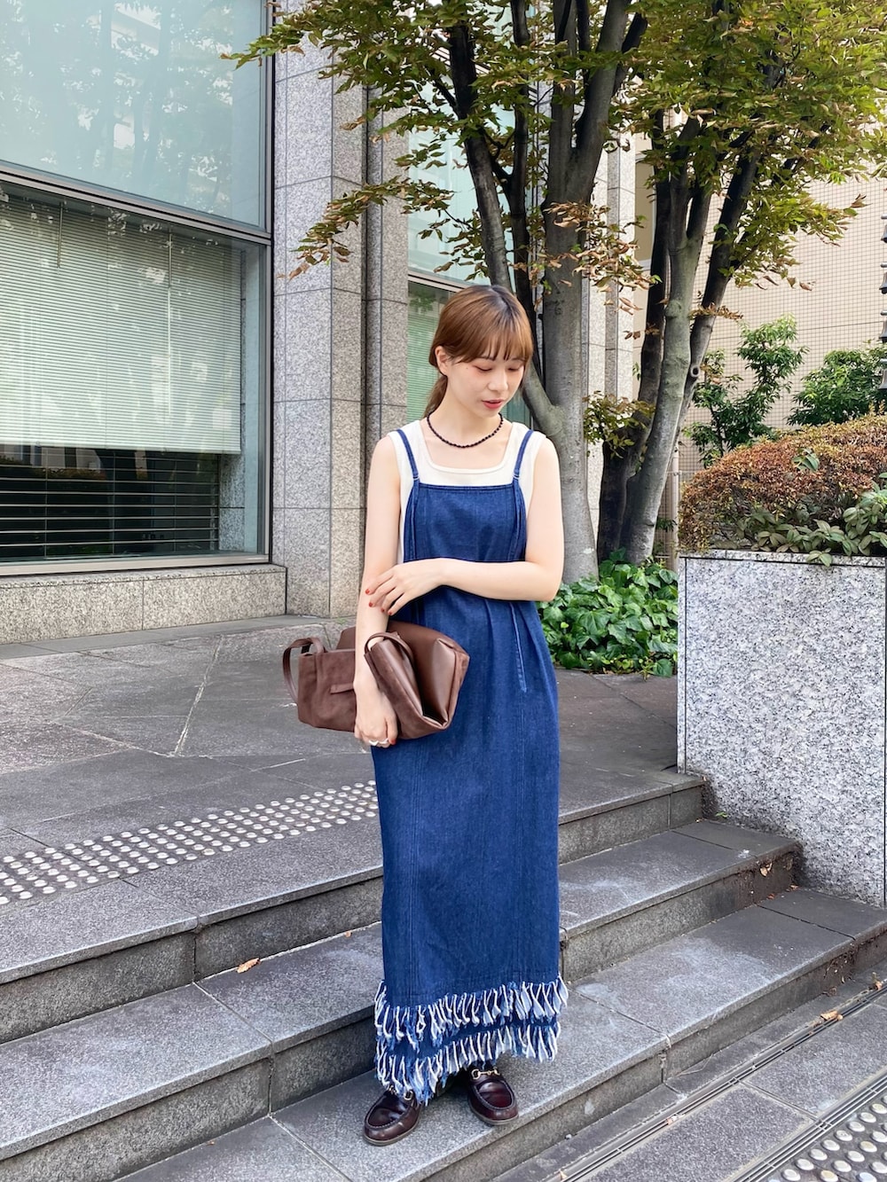 ブルー系のワンピース、ブラウン系のトートバッグ、ホワイト系のタンクトップを着用したレディースの秋コーディネートの5枚目の写真