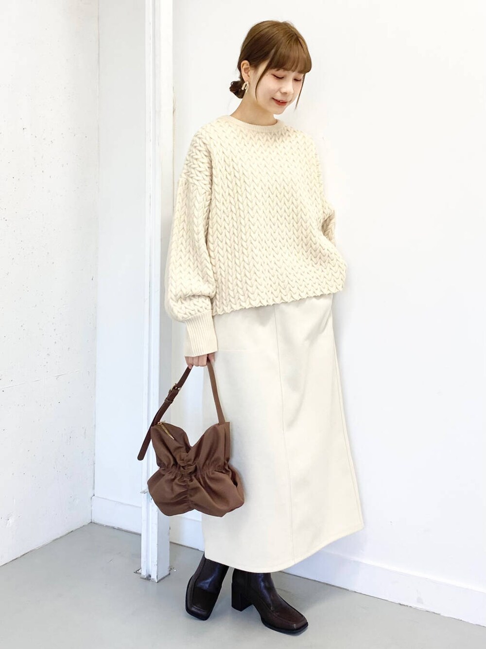 ブラウン系のハンドバッグ、ブラウン系のブーツ、ホワイト系のスカートを着用したレディースの冬コーディネートの4枚目の写真