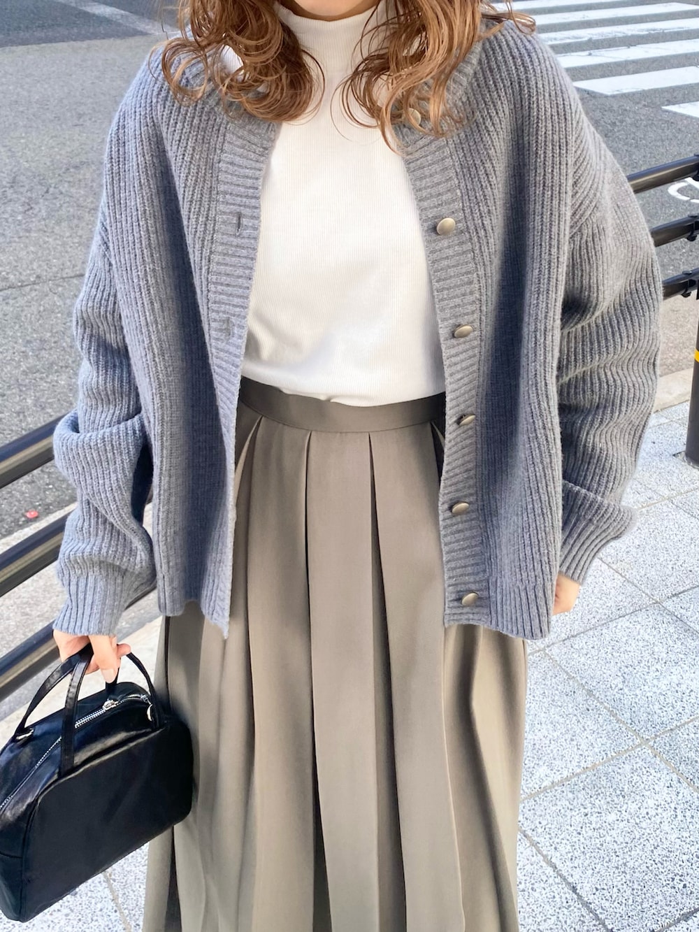 ブラウン系のローファー、ブラック系のショルダーバッグ、グリーン系のスカートを着用したレディースの秋コーディネートの4枚目の写真