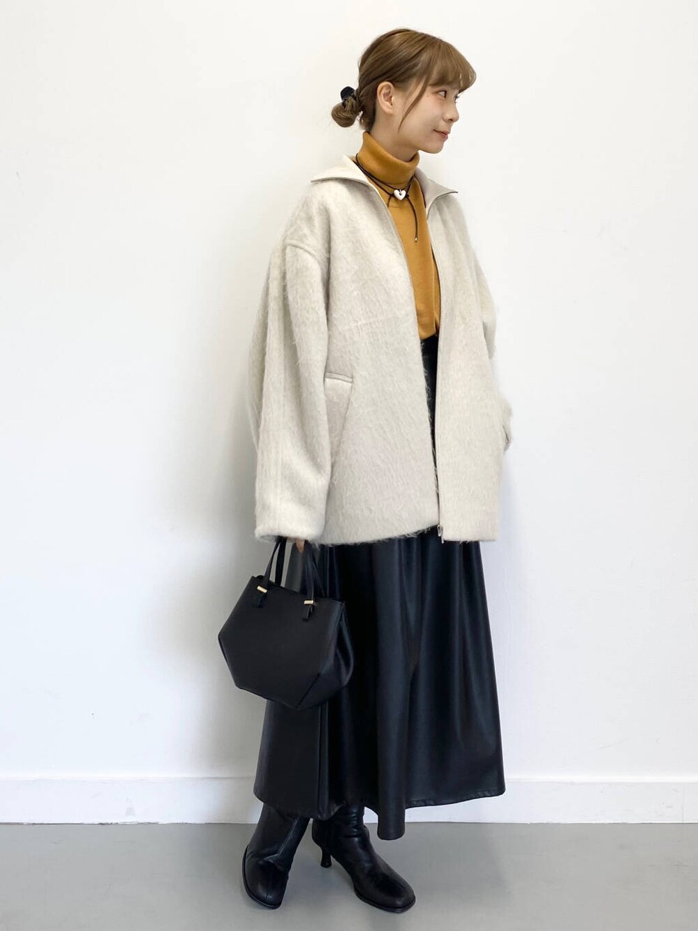 イエロー系のニット/セーター、ブラック系のショルダーバッグ、ブラック系のブーツを着用したレディースの冬コーディネートの6枚目の写真