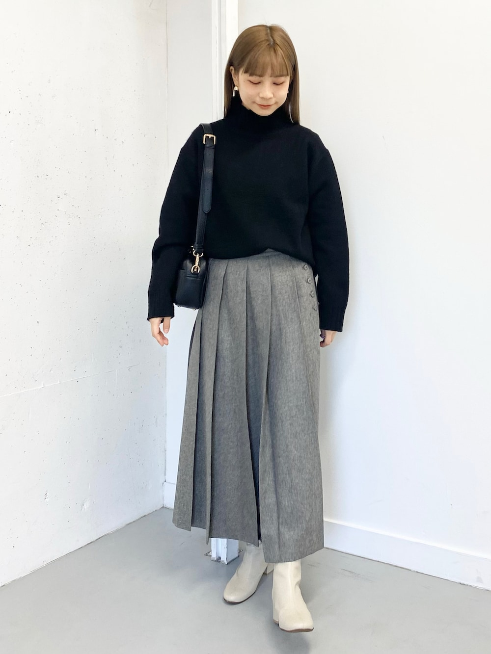 グレー系のスカート、ホワイト系のブーツ、ブラック系のショルダーバッグを着用したレディースの冬コーディネートの5枚目の写真