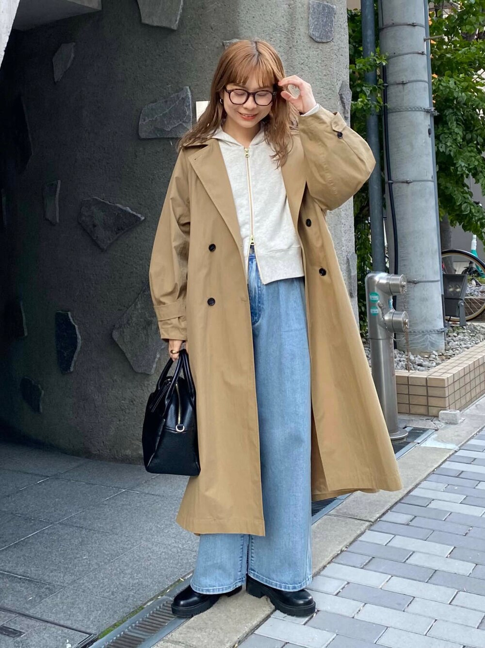 ブラック系のボストンバッグ、ブラック系のブーツ、ベージュ系のパーカーを着用したレディースの冬コーディネートの2枚目の写真