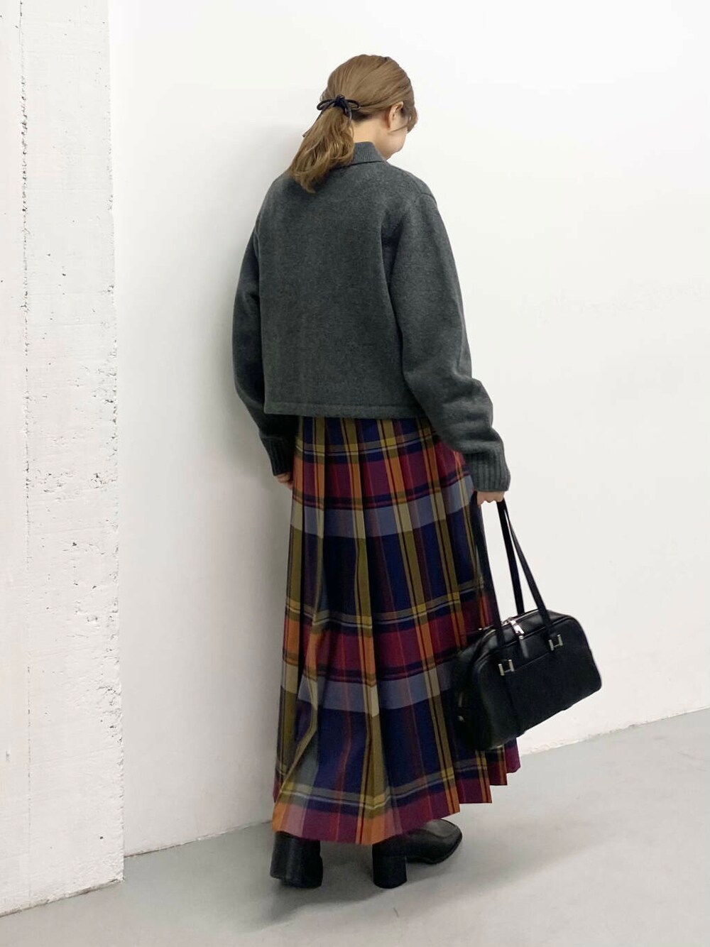 ブラック系のボストンバッグ、ブラック系のブーツ、ブルー系のスカートを着用したレディースの秋コーディネートの4枚目の写真