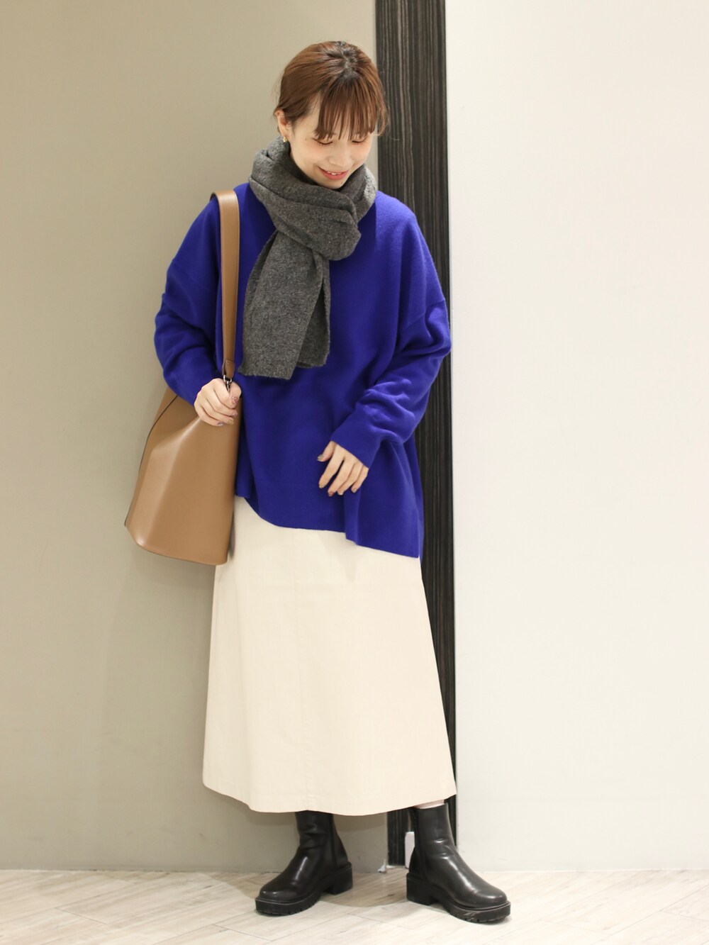 ブラウン系のショルダーバッグ、ホワイト系のスカート、ブラック系のブーツを着用したレディースの冬コーディネートの2枚目の写真