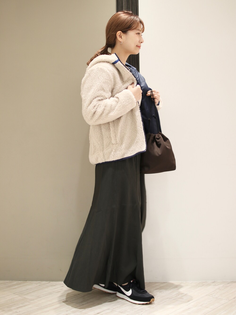 ブラック系のスニーカー、グレー系のスカート、ブラウン系のショルダーバッグを着用したレディースの秋コーディネートの5枚目の写真