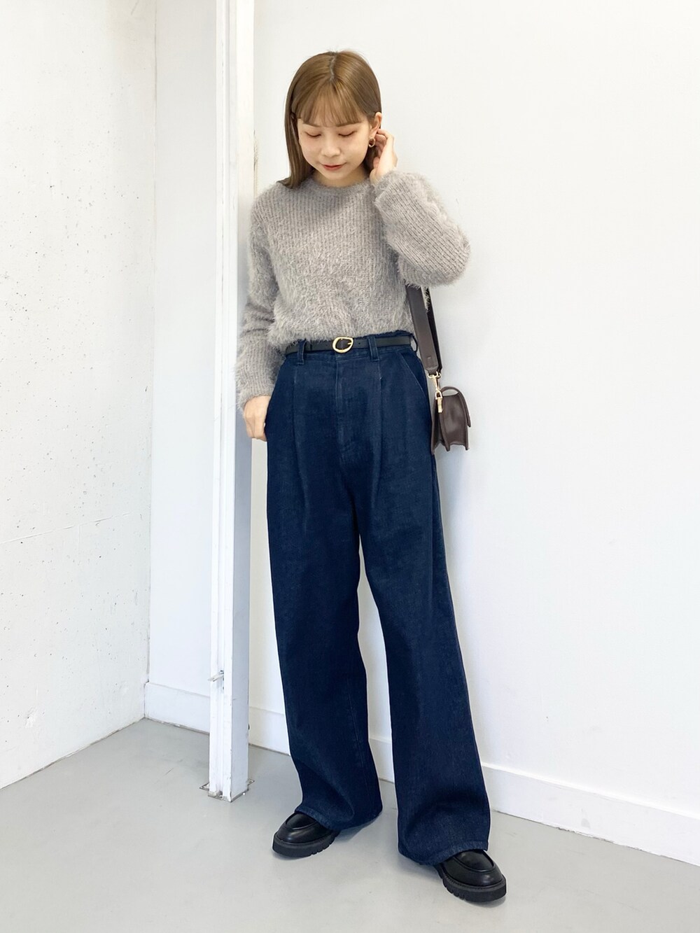 ブラック系のローファー、ブルー系のデニムパンツ、グレー系のニット/セーターを着用したレディースの冬コーディネートの5枚目の写真