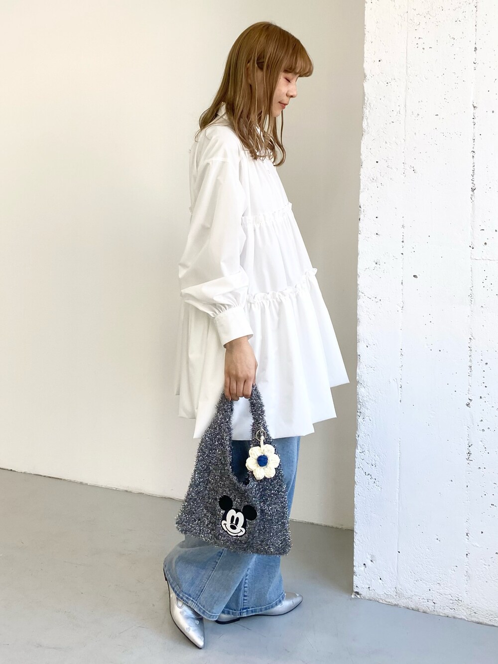 ホワイト系のワンピース、ブルー系のデニムパンツ、ブラック系のトートバッグを着用したレディースの冬コーディネートの3枚目の写真