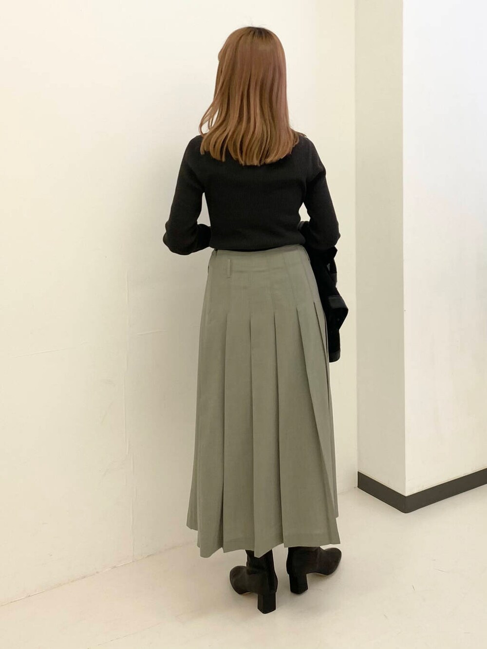 グレー系のスカート、グリーン系のニット/セーター、ブラック系のブルゾンを着用したレディースの秋コーディネートの6枚目の写真