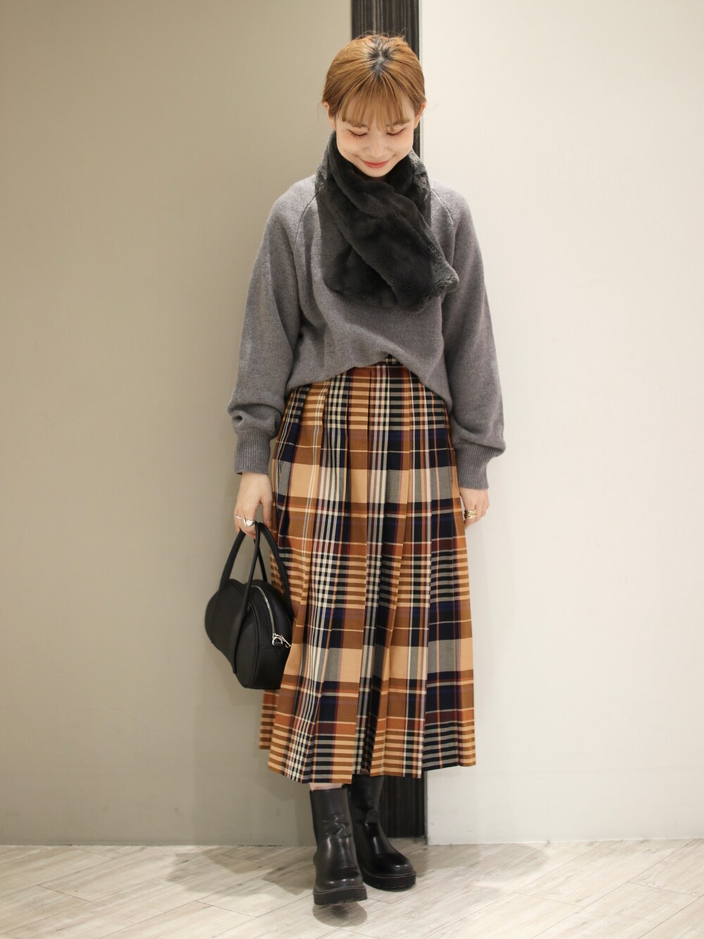 グレー系のニット/セーター、オレンジ系のスカート、ブラック系のショルダーバッグを着用したレディースの秋コーディネートの3枚目の写真