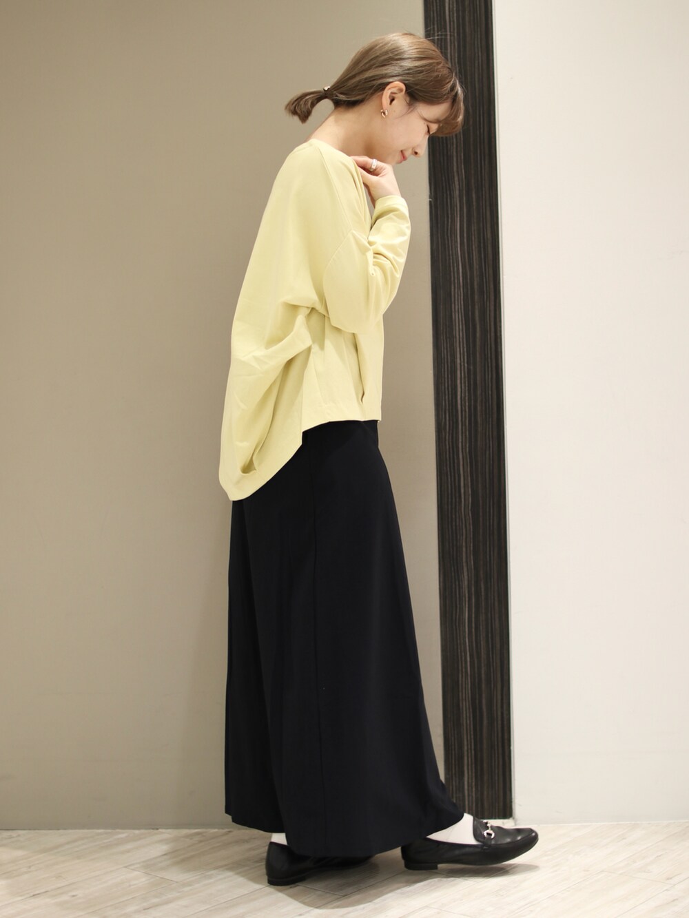 ベージュ系のトートバッグ、イエロー系のTシャツ/カットソー、ブルー系のスカートを着用したレディースの冬コーディネートの3枚目の写真