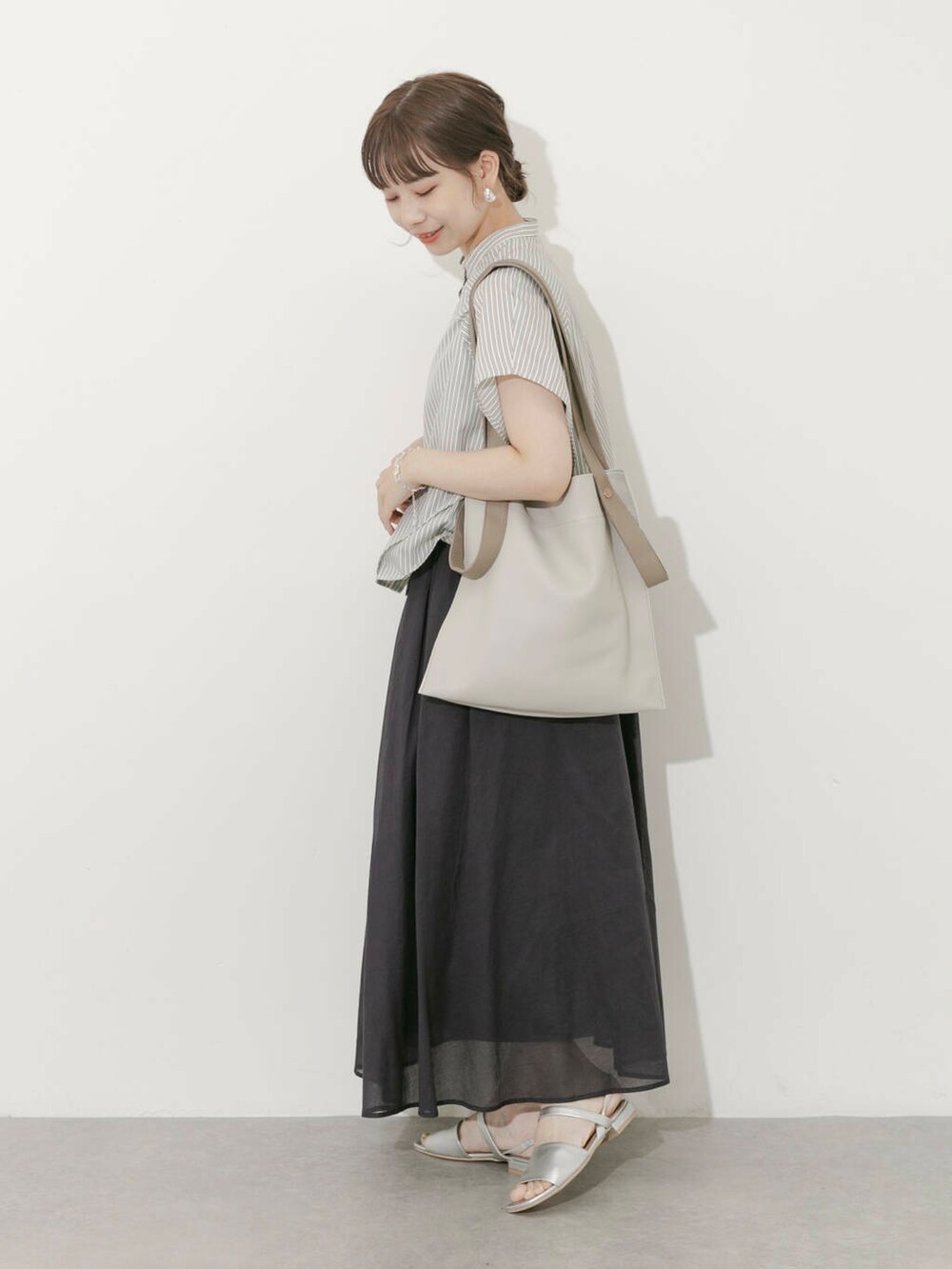 グレー系のスカート、ホワイト系のシャツ/ブラウス、シルバー系のサンダルを着用したレディースの夏コーディネートの3枚目の写真