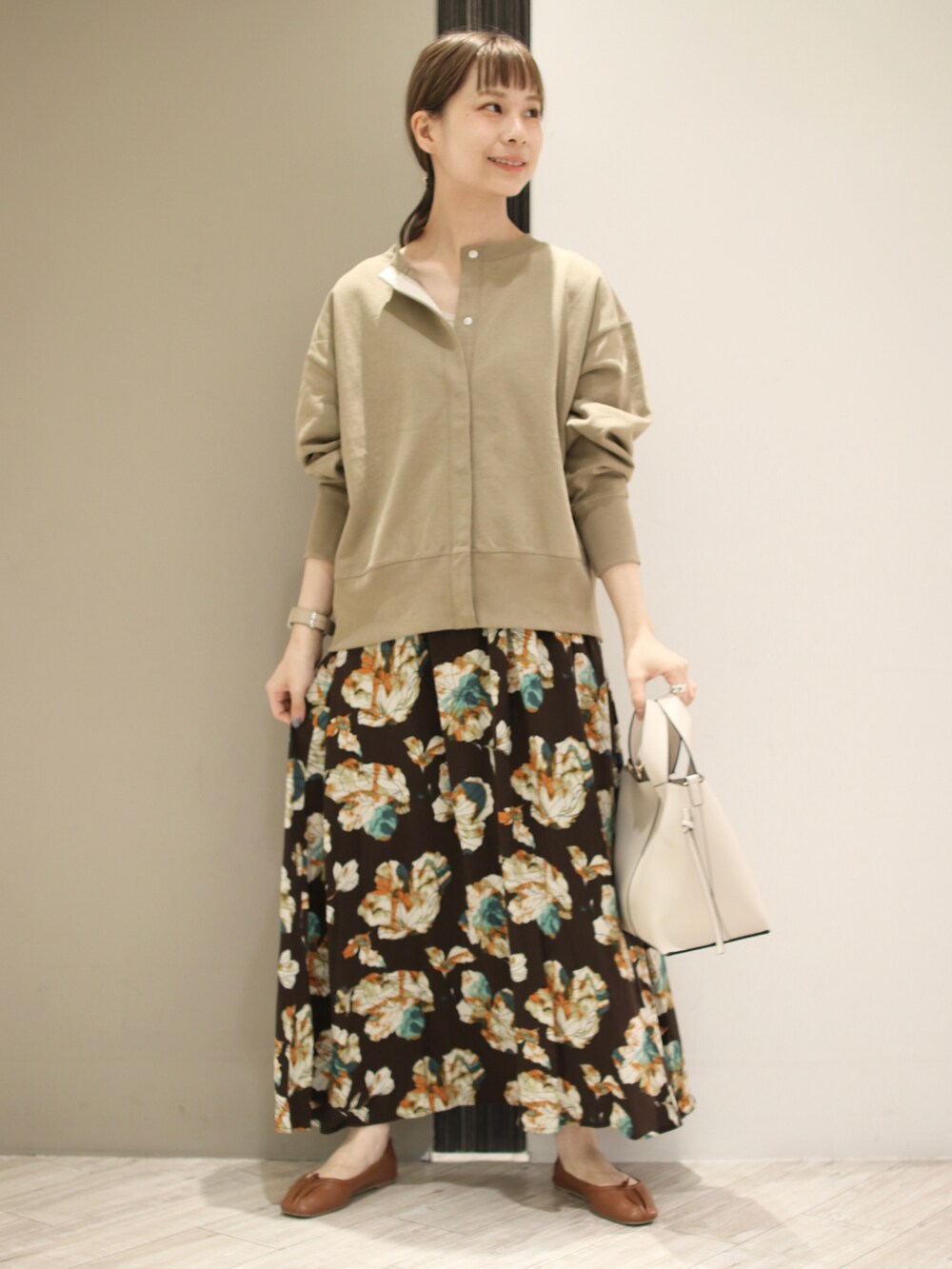 ホワイト系のトートバッグ、ベージュ系のスウェット、ブラウン系のスカートを着用したレディースの秋コーディネートの3枚目の写真