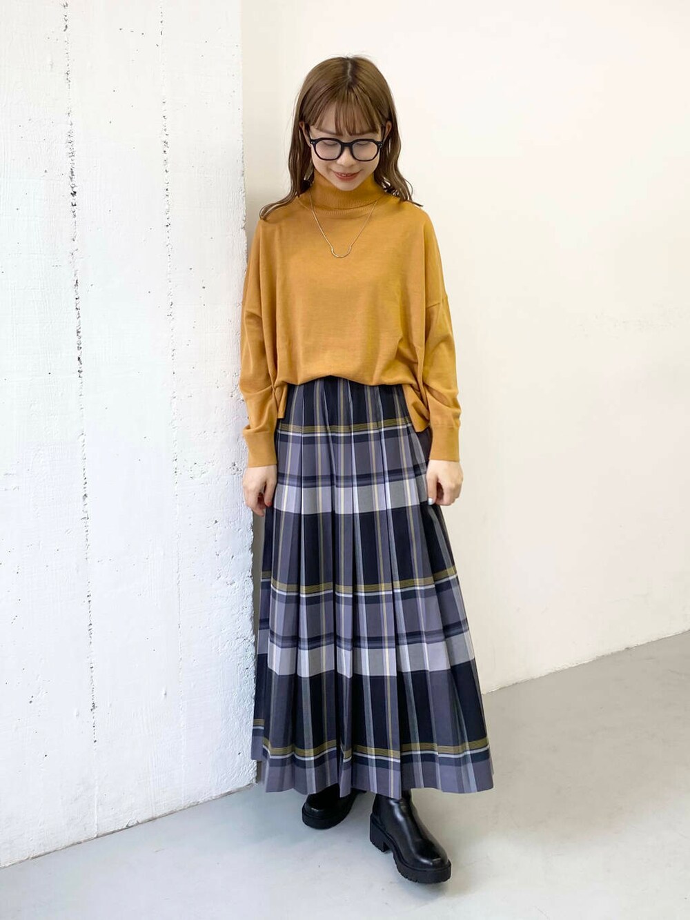 イエロー系のニット/セーター、ブラック系のブーツ、ブラック系のスカートを着用したレディースの秋コーディネートの4枚目の写真